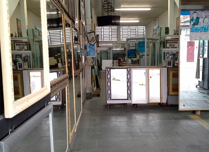 Interior da loja da Vitrais Celso, com amostras de espelhos e molduras expostas