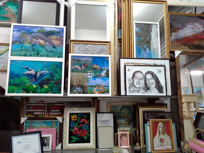 Parede do ateliê com dezenas de quadros emoldurados pela Vitrais Celso