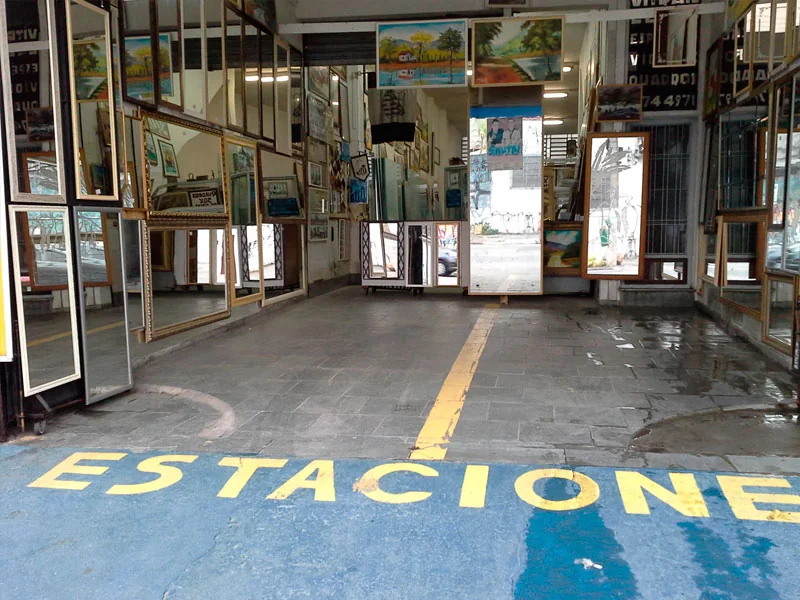 Fachada da sede da Vitrais Celso, com molduras expostas e a palavra Estacione pintada no piso